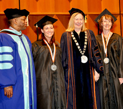 Dean Gary Lacy looks on as graduate Christine Galletta, Acting President Meg Benke and Christine's mother and fellow graduate Anne McDonald Galletta share a smile.