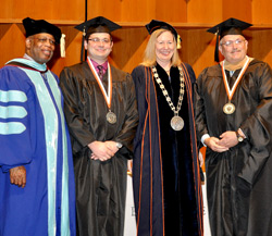 Dean Gary Lacy, left, joins graduate Gavin Michael Strube, Acting President Meg Benke and Gavin’s father Michael Strube on stage at graduation. Gavin Michael earned his bachelor’s and his father earned an MBA.