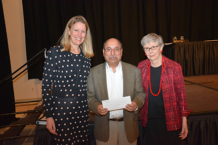 Man with award flanked by two women.